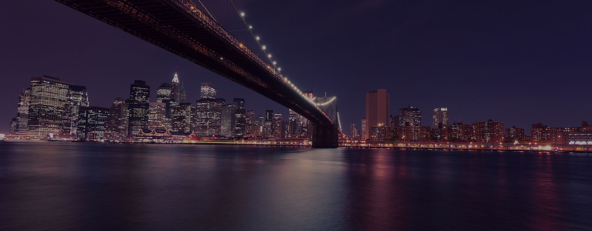 Skyline of NYC and the Brooklyn Bridge at night.