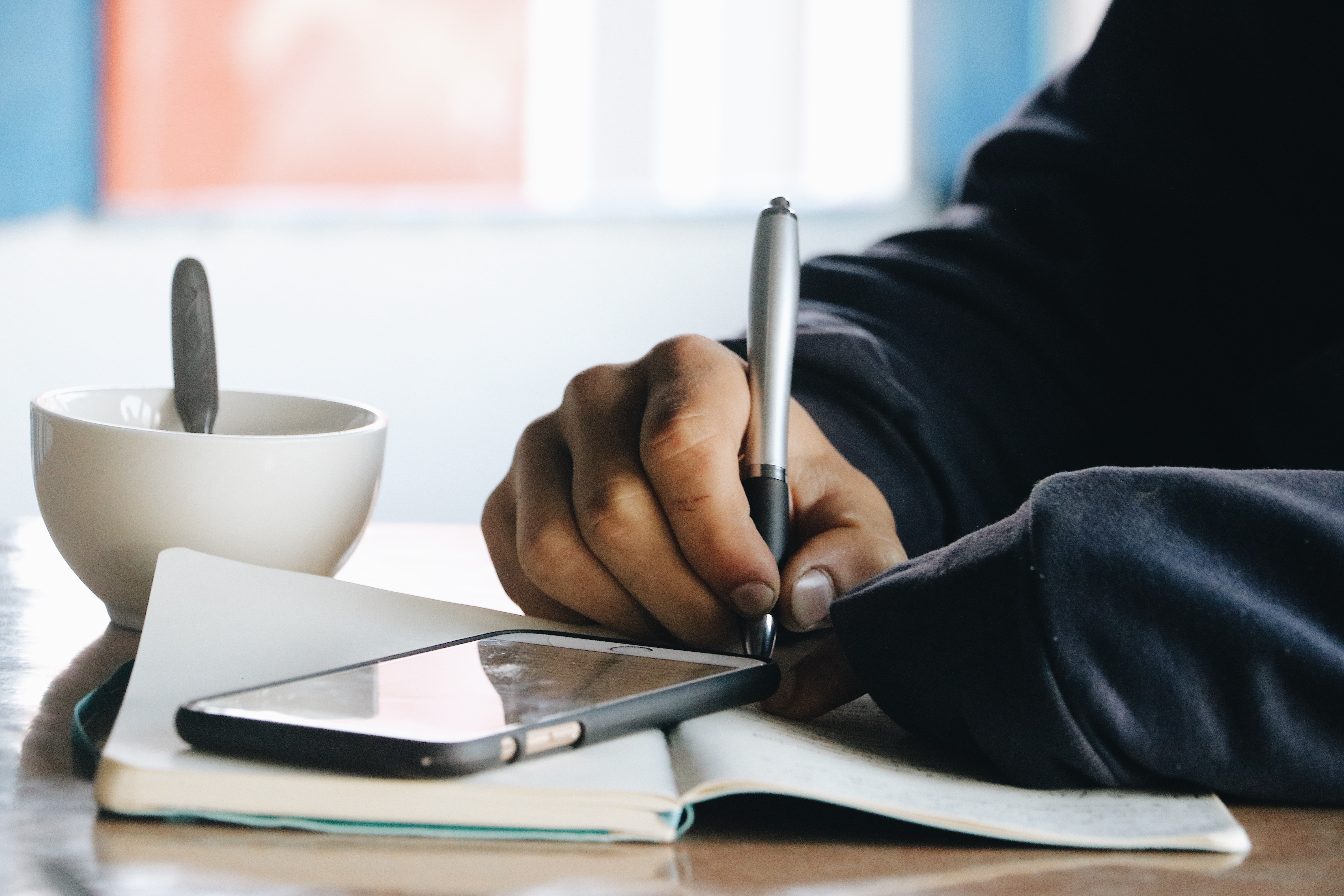 Person sitting at a table and writing in a journal.